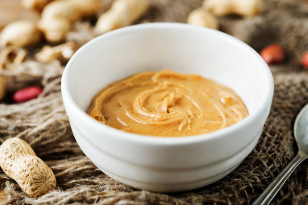 istock Peanut butter with peanuts on a dark wood background 1187872714