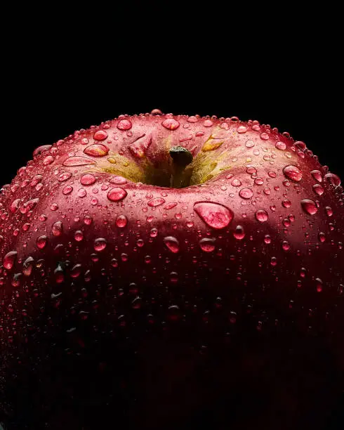 Red apple with large drops of water. Close up photo. Black background.