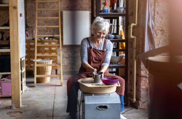 starsza kobieta wykonująca ceramiczną pracę z kołem garncarskim - koło garncarskie zdjęcia i obrazy z banku zdjęć