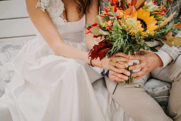 Bride and groom holding hands . Wedding rings and bride's bouquet detail. stock photo