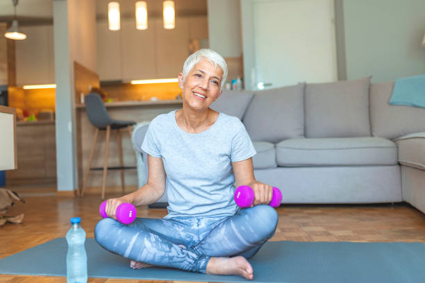 istock Senior lady smiling at the camera whilst using dumbbells. 1187885611