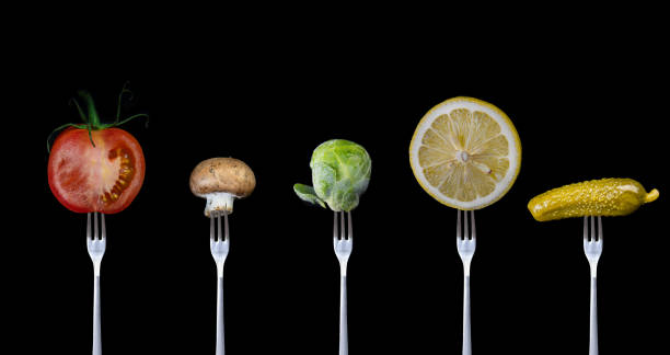 istock Five different vegetables on a fork, Tomato, mushroom, brussel sprout, lemon and a pickle on black background. 1187895048