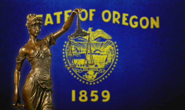 Lady Justice before a flag of Oregon Close-up of a small bronze statuette of Lady Justice before a flag of Oregon. oregon us state photos stock pictures, royalty-free photos & images