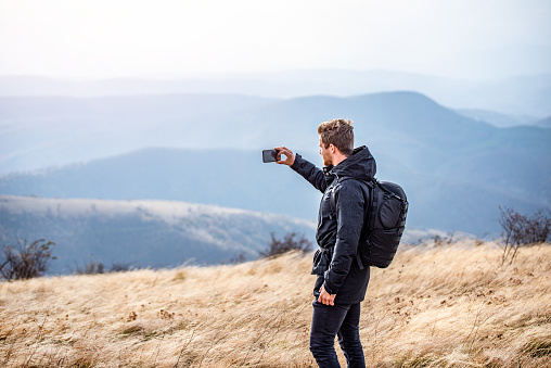Young man taking a photo of beautiful mountain range.