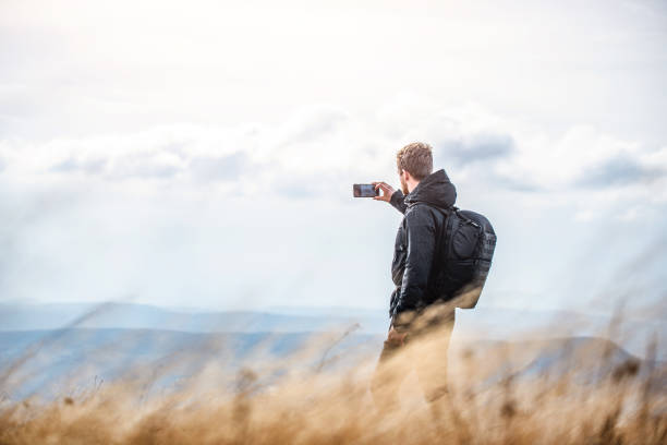 Young man taking a photo of beautiful mountain range.