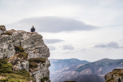 Young man meditating on a mountain top.