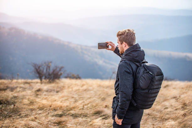 istock Young man taking a photo of beautiful mountain range. 1187897089