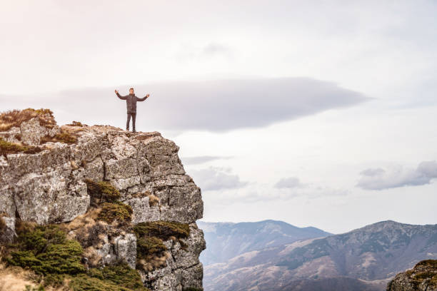 istock Ecstatic young man standing on the top of the mountain. 1187897149