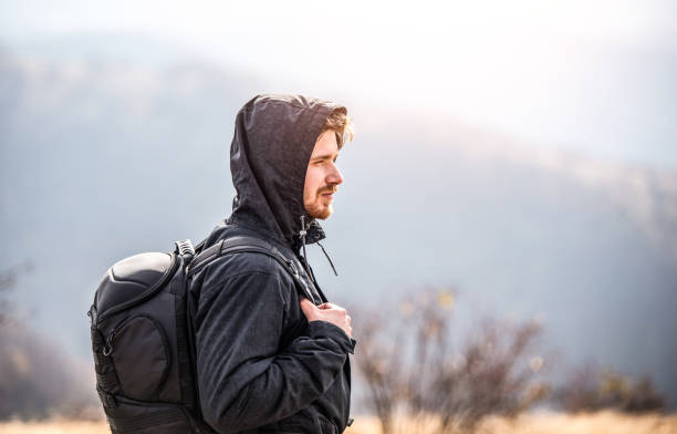 young man hiking on a mountain on a cold day. - footpath field nature contemplation imagens e fotografias de stock