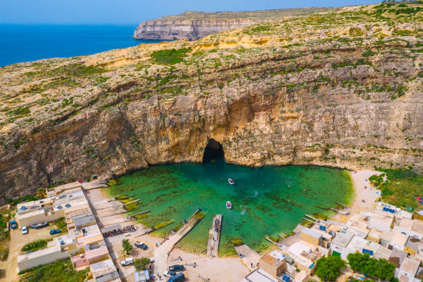 el mar interior y barco turístico. dwejra es una laguna de agua de mar en la isla de gozo. vista aérea del túnel marino cerca de la ventana de azure. mar mediterráneo. país de malta - gozo malta natural arch natural phenomenon fotografías e imágenes de stock