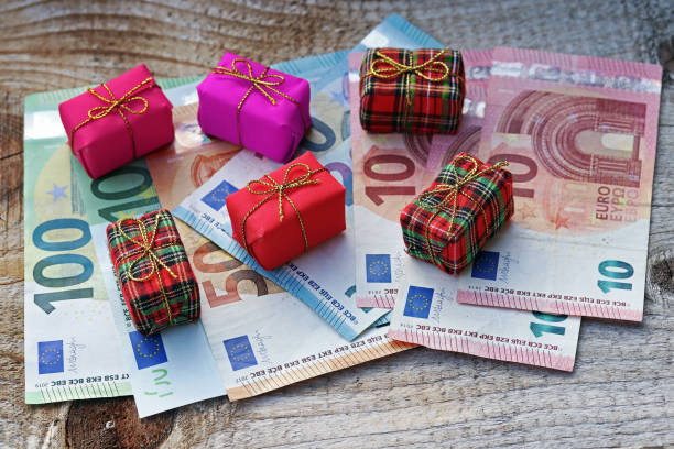 combien d'euros est dépensé pour les cadeaux de noel? les cadeaux de noel coûtent de l'argent - currency perks gift bow photos et images de collection