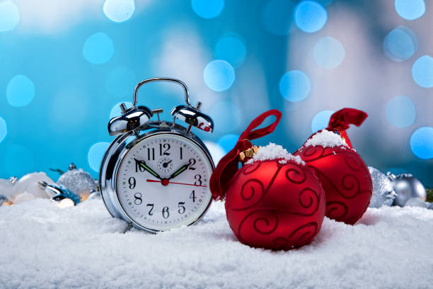 This is a photo of an Alarm Clock and Christmas Ornaments in the bed sitting in a snow background.