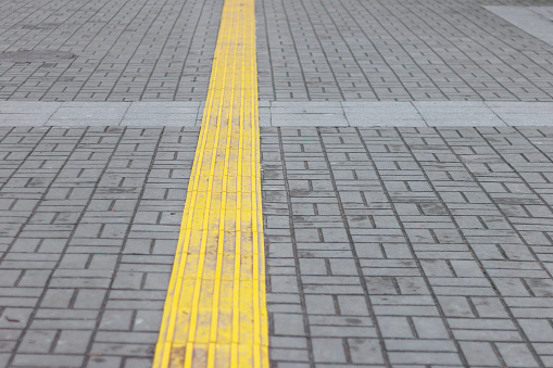 yellow line for blind people on gray pavers. perspective.copy space. pedestrian