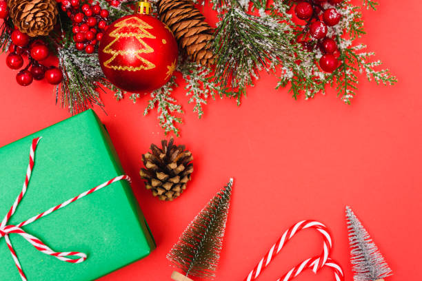 istock Christmas green gift box and decorations, fir tree branches on red background 1187936431