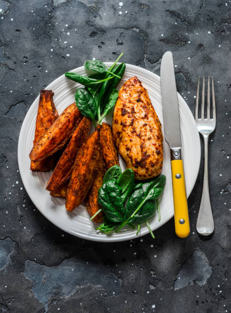 gebackene hähnchenbrust mit süßkartoffeln und spinat auf dunklem hintergrund, ansicht von oben. ausgewogenes gesundes mittagessen - spinach vegetable plant freshness stock-fotos und bilder