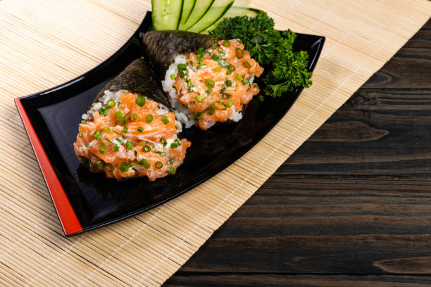 istock Salmon temaki sushi on black plate in black background 1187944255