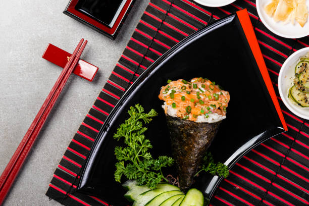Salmon temaki sushi on black plate on gray background. Japanese cuisine. Top view Salmon temaki sushi on black plate on gray background. Japanese cuisine. Top view. sunomono stock pictures, royalty-free photos & images