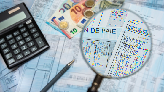 Nómina francesa con calculadora, dinero en efectivo en euros y lupa photo