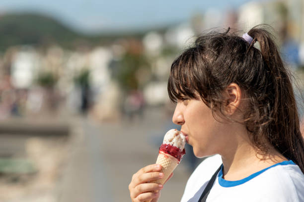 девушка ест вкусное мороженое - child looking messy urban scene стоковые фото и изображения