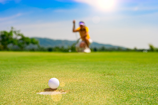 Golf ball on tee with grass and green blurred background