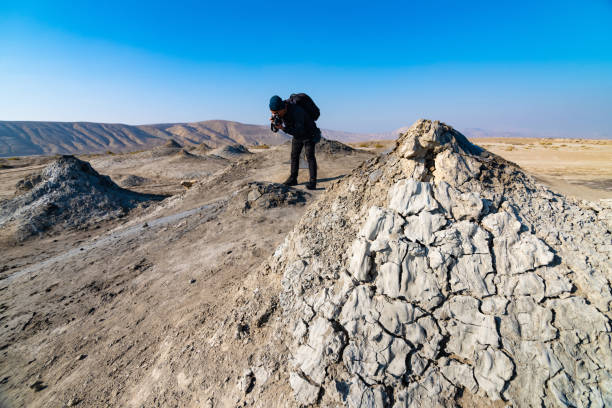 Mud volcano with tourist in background in gobustan national park ,Azerbaijan.Bubbling crater of a mud volcano. Mud volcano with tourist in background in gobustan national park ,Azerbaijan.Bubbling crater of a mud volcano. mud volcano stock pictures, royalty-free photos & images