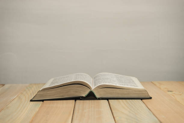istock Open  Bible on a old wooden table and white wall background. Religion concept. 1187975783