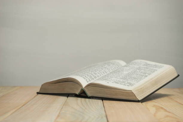 istock Open  Bible on a old wooden table and white wall background. Religion concept. 1187976316