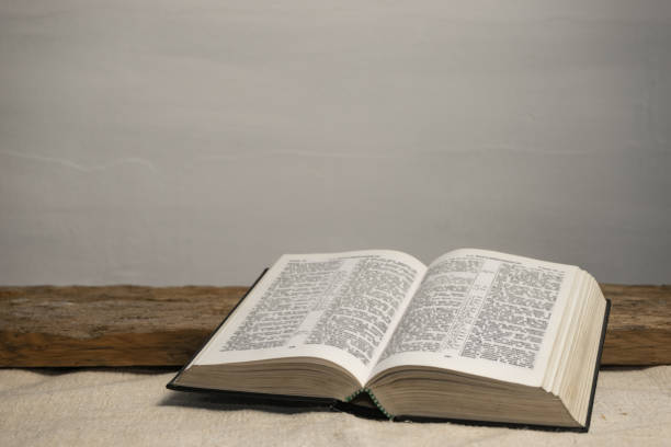 istock Open Holy Bible on a old wooden table and white wall background. Religion concept. 1187976457