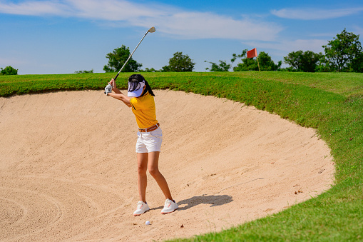 woman golfer hit sand ground exposure trying to approach or reach to hole final destination on the green, hit sand bunker attempt by woman golfer