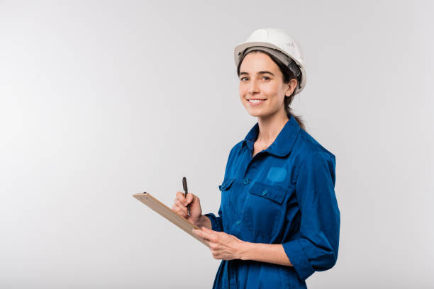 istock Happy young female builder in blue workwear and hardhat making notes in document 1187980396