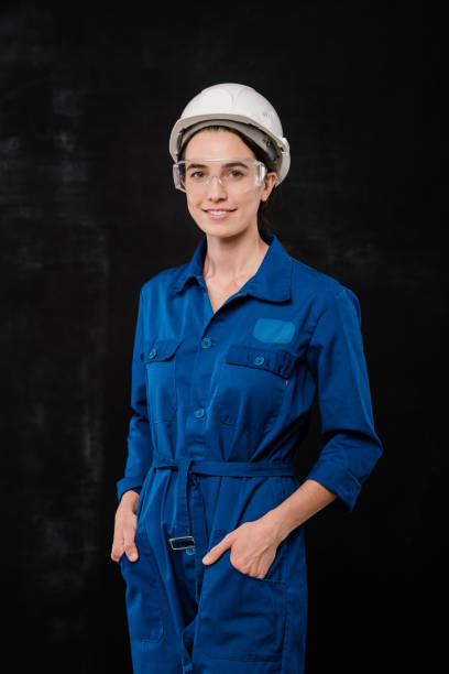 istock Young female builder in hardhat and blue coveralls keeping hands in pockets 1187980408