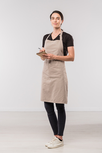 Bonita joven camarera de café haciendo notas sobre el orden del cliente en aislamiento photo