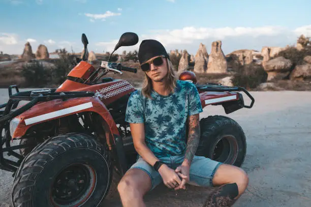 Photo of Man sitting at ATV Quad Bike in front of mountains landscape in Cappadocia