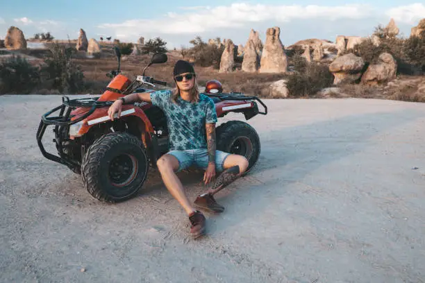 Photo of Man sitting at ATV Quad Bike in front of mountains landscape in Cappadocia