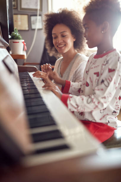 mother with child on christmas play music on piano. concept of holidays and family happiness. - family american culture african culture black imagens e fotografias de stock