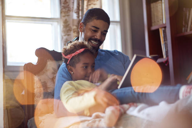 istock holidays and celebration concept - Father and daughter spending Christmas time together, daddy reading fairy tales 1187991084