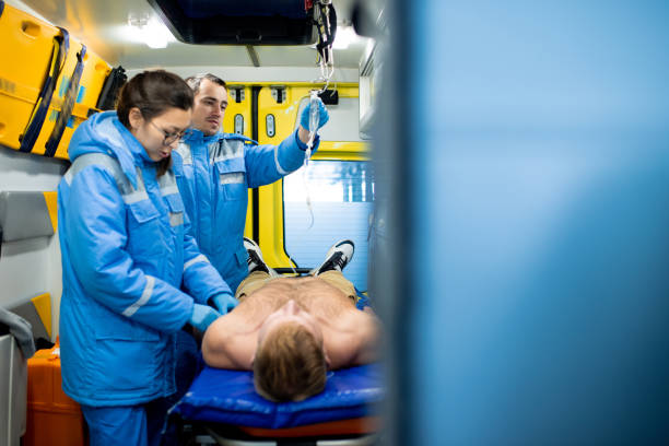 istock Paramedic examining unconscious shirtless man while colleague holding dropper 1187991216