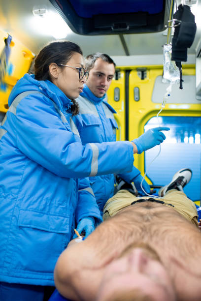 istock Two young paramedics preparing dropper for sick man inside ambulance car 1187991270