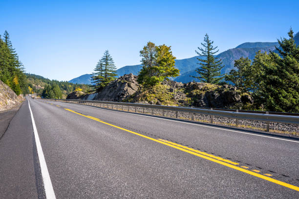 istock Smooth road between cliffs with yellowed autumn trees and a protective fence in Columbia Gorge 1187992170