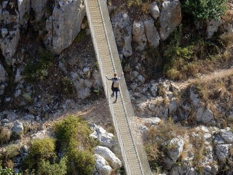 Matera, Basilicata, Italy - November 3, 2019: Tourist on the Tibetan bridge that crosses the Gravina Torrent