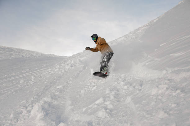 istock Disabled man without one hand riding on the snowboard 1187993457