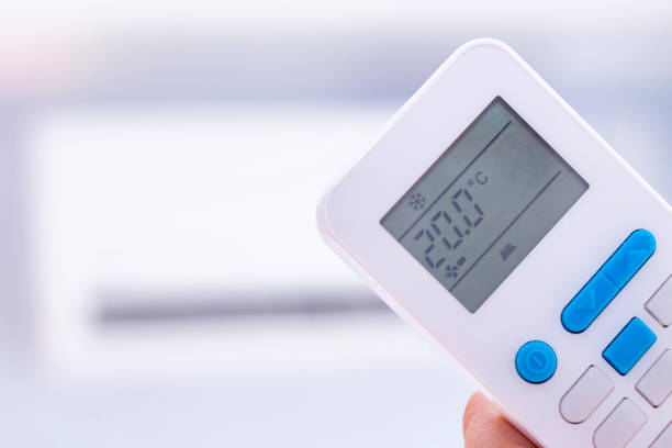 istock hand using remote controler. Hand holding rc and adjusting temperature of air conditioner mounted on a white wall. Indooor comfort temperature. Health concepts and energy savings. 1187993466