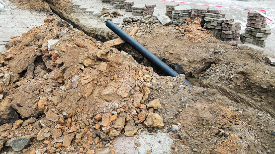 Laying installation of a new cable in a plastic pipe. Digging drilling of the earth for pipe replacement, sewer.Work with drainage system, water supply and electric cable laying.