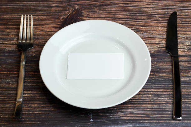 istock Empty plate on table with cutlery and blank business card, top view. Message for visitor of restaurant or cafe. Business lunch without tips concept. 1187996171