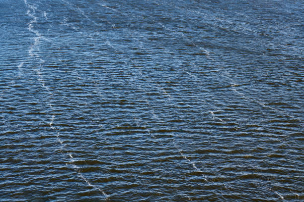 Foam line pollution in river. Factory oil emissions, environmental pollution. Deep blue river with strong current.