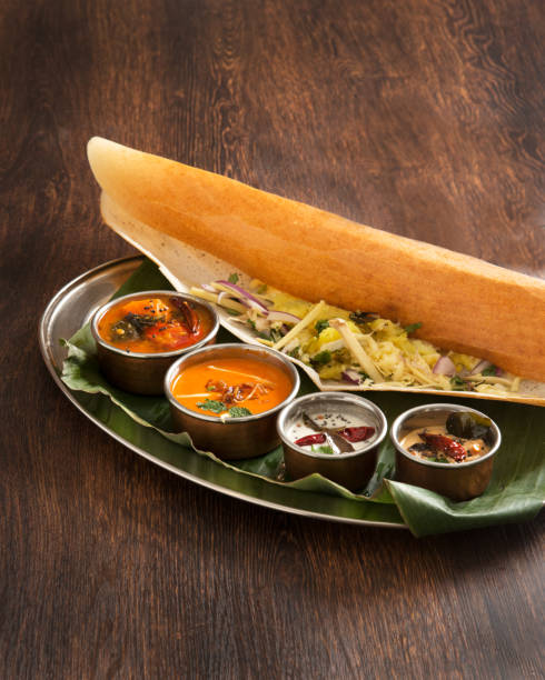 A plate of masala dosa A plate of masala dosa, a South Indian cuisine and 4 types of curry
on a wooden table. thosai stock pictures, royalty-free photos & images