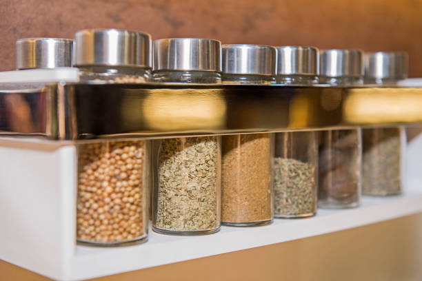 Closeup of kitchen spice rack with jars in a row Abstract closeup detail still life of spice rack in kitchen with glass jars in a row spice rack stock pictures, royalty-free photos & images