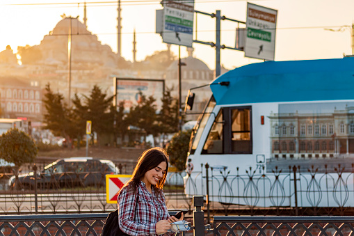 Young girl in front of a moving train using smartphone while holding a map. Istanbul the capital of Turkey, eastern tourist city.
