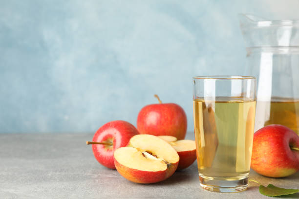 istock Red apples and glasses with juice on grey background, space for text 1187998759