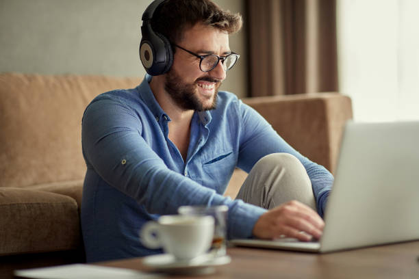 istock man with headphones using laptop in his home 1187999616